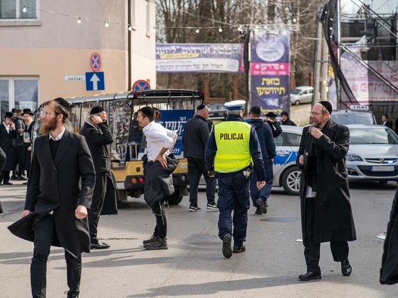 Zdjęcie przedstawia zabezpieczenie pielgrzymki Chasydów do Leżajska. Na zdjęciach znajdują się umundurowani funkcjonariusze Policji oraz pielgrzymi narodowości żydowskiej.