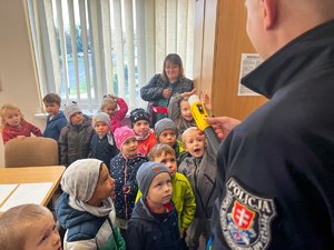 Zdjęcie przedstawia grupę dzieci i umundurowanego funkcjonariusza pokazującego urządzenie do badania stanu trzeźwości.