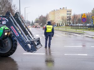 Zdjęcie przedstawia umundurowanych funkcjonariuszy z Komendy Powiatowej Policji w Leżajsku oraz pojazdy służbowe oznakowane, biorące udział w zabezpieczeniu protestu rolników w dniu dwudziestego lutego. W tle widać pojazdy oraz maszyny rolnicze.