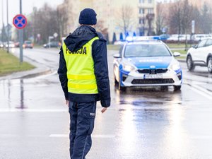 Zdjęcie przedstawia umundurowanych funkcjonariuszy z Komendy Powiatowej Policji w Leżajsku oraz pojazdy służbowe oznakowane, biorące udział w zabezpieczeniu protestu rolników w dniu dwudziestego lutego. W tle widać pojazdy oraz maszyny rolnicze.