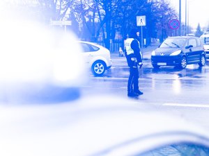 Zdjęcie przedstawia umundurowanych funkcjonariuszy z Komendy Powiatowej Policji w Leżajsku oraz pojazdy służbowe oznakowane, biorące udział w zabezpieczeniu protestu rolników w dniu dwudziestego lutego. W tle widać pojazdy oraz maszyny rolnicze.