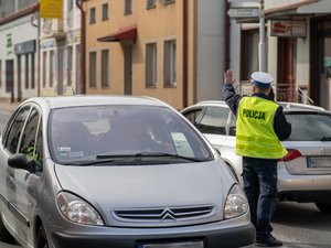 Zdjęcia przedstawiają umundurowanych policjantów z leżajskiej komendy. Są oni odwróceni tyłem do obiektywu aparatu. W tle widać pielgrzymujących do leżajska chasydów. Są oni zamazani. Widoczne też są samochody, również zamazane.