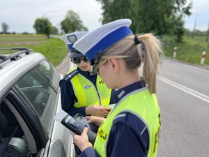 Na zdjęciu widoczni są umundurowani funkcjonariusze Policji. Zdjęcie wykonane na zewnątrz.