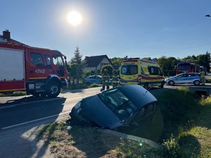 Zdjęcie przedstawia miejsce zdarzenia drogowego w Wierzawicach. Na zdjęciu widać uszkodzony pojazd marki Volkswagen. W kadrze zdjęcia widoczny jest również samochód straży pożarnej oraz radiowóz policji. Na zdjęciu widoczni są również umundurowani funkcjonariusze straży pożarnej oraz policji.