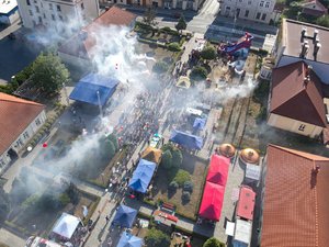 Zdjęcia przedstawiają plac Muzeum Ziemi Leżajskiej z lotu ptaka. Widać na nim scenę oraz zadymienie, w wyniku odpalonych rac. Przed sceną widać osoby oraz pojazdy.