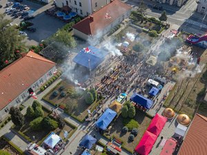 Zdjęcia przedstawiają plac Muzeum Ziemi Leżajskiej z lotu ptaka. Widać na nim scenę oraz zadymienie, w wyniku odpalonych rac. Przed sceną widać osoby oraz pojazdy.