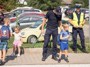 Zdjęcia przedstawiają umundurowanych funkcjonariuszy Komendy Powiatowej Policji w Leżajsku, którzy znajdują się pod szkołami na terenie powiatu leżajskiego i rozmawiają z uczestnikami ruchu drogowego, którzy korzystają z przejścia dla pieszych. Policjanci ubrani są w odblaskowe kamizelki.