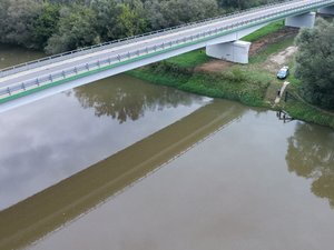 Zdjęcia przedstawiają umundurowanego funkcjonariusza oraz oznakowany radiowóz Policji podczas działań mających na celu monitorowanie stanu rzek i potoków na terenie powiatu leżajskiego.