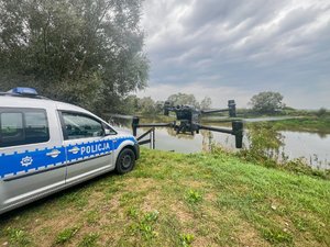 Zdjęcia przedstawiają umundurowanego funkcjonariusza oraz oznakowany radiowóz Policji podczas działań mających na celu monitorowanie stanu rzek i potoków na terenie powiatu leżajskiego.