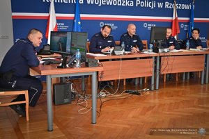 Zdjęcia przedstawiają umundurowanych funkcjonariuszy Policji w trakcie przebiegu eliminacji do ogólnopolskiego konkursu służby dyżurnej. Na zdjęciach widać zmagania policjantów podczas testów i zadań praktycznych. Wszystko odbywa się w zamkniętej sali konferencyjnej.