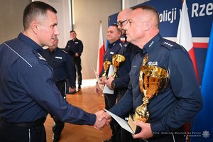 Zdjęcia przedstawiają umundurowanych funkcjonariuszy Policji w trakcie przebiegu eliminacji do ogólnopolskiego konkursu służby dyżurnej. Na zdjęciach widać zmagania policjantów podczas testów i zadań praktycznych. Wszystko odbywa się w zamkniętej sali konferencyjnej.