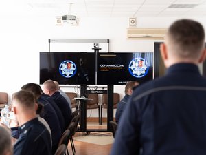 Zdjęcia przedstawia funkcjonariuszy policji wraz z samorządowcami, prokuratorem, sędzią oraz strażakiem podczas odprawy rocznej w leżajskiej komendzie. Odprawa odbyła się w budynku Komendy Powiatowej Policji w Leżajsku. Na zdjęciach znajdują się policjanci oraz osoby cywilne. Widoczny jest telewizor na którym wyświetlana jest prezentacja.