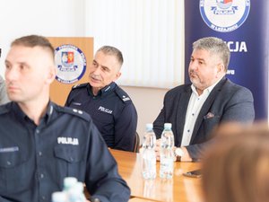 Zdjęcia przedstawia funkcjonariuszy policji wraz z samorządowcami, prokuratorem, sędzią oraz strażakiem podczas odprawy rocznej w leżajskiej komendzie. Odprawa odbyła się w budynku Komendy Powiatowej Policji w Leżajsku. Na zdjęciach znajdują się policjanci oraz osoby cywilne. Widoczny jest telewizor na którym wyświetlana jest prezentacja.