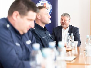 Zdjęcia przedstawia funkcjonariuszy policji wraz z samorządowcami, prokuratorem, sędzią oraz strażakiem podczas odprawy rocznej w leżajskiej komendzie. Odprawa odbyła się w budynku Komendy Powiatowej Policji w Leżajsku. Na zdjęciach znajdują się policjanci oraz osoby cywilne. Widoczny jest telewizor na którym wyświetlana jest prezentacja.