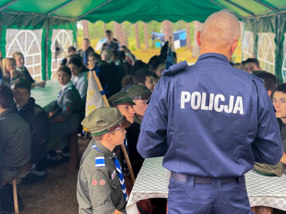 Zdjęcia przedstawiają spotkanie profilaktyczne policjantów z uczestnikami obozu harcerskiego w Dąbrowicy.