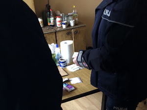 Na zdjęciu widoczni są policjanci, a w tle na stole znajdują się lekarstwa.