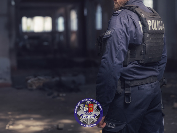 Zdjęcie przedstawia umundurowanego policjanta, posiadającego na sobie kamizelkę taktyczną. Jest noc. W tle są budynki.