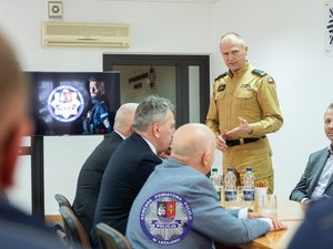 Zdjęcia przedstawiają przebieg odprawy rocznej w auli Komendy Powiatowej Policji w Leżajsku. Na zdjęciach widać umundurowanych funkcjonariuszy oraz osoby cywilne - zaproszonych gości, przedstawicieli samorządów powiatu leżajskiego. Zdjęcia wykonane są wewnątrz budynku.