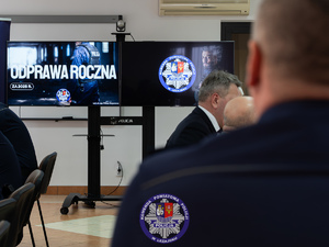 Zdjęcia przedstawiają przebieg odprawy rocznej w auli Komendy Powiatowej Policji w Leżajsku. Na zdjęciach widać umundurowanych funkcjonariuszy oraz osoby cywilne - zaproszonych gości, przedstawicieli samorządów powiatu leżajskiego. Zdjęcia wykonane są wewnątrz budynku.