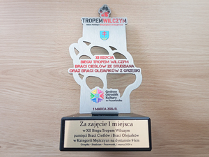 Zdjęcie przedstawia oprawę na zakończenie biegu Tropem Wilczym w Przeworsku oraz statuetkę.