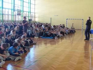 Zdjęcie przedstawiają umundurowanego policjanta podczas prelekcji w Zespole Szkół im. Jana Pawła II w Brzózie Królewskiej