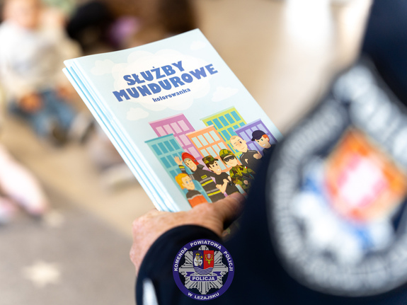 Zdjęcia przedstawiają przebieg spotkania profilaktycznego podopiecznych ze żłobka w Giedlarowej z dzielnicowym z Komendy Powiatowej Policji w Leżajsku. Umundurowany funkcjonariusz opowiadał dzieciom o pracy policjanta.