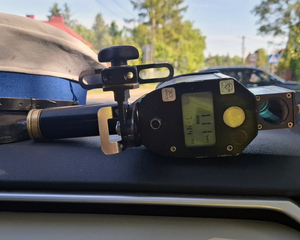 Na zdjęciu widoczne jest urządzenie kontrolno-pomiarowe, ze wskazaniem 111km/h. Po lewej stronie widoczny jest kawałem czapki policyjnej.